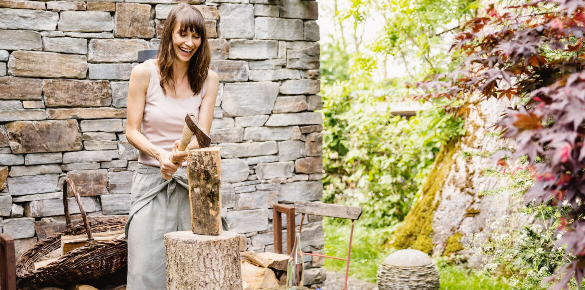 To Do List Before Lighting Your First Fire Of The Season- a woman cut her wood for the winter