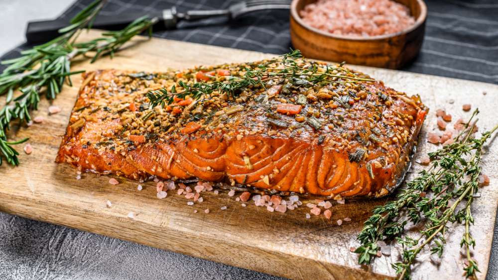 Low n slow smoked salmon with herbs and spices on wood cutting board.